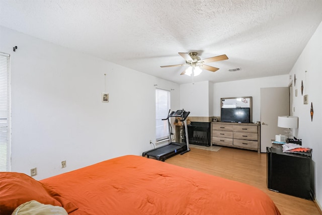 bedroom with ceiling fan, a textured ceiling, and light hardwood / wood-style floors