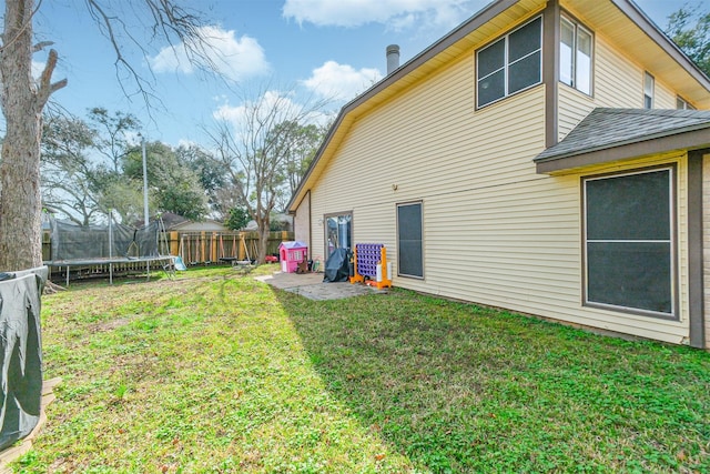 rear view of property with a trampoline and a yard