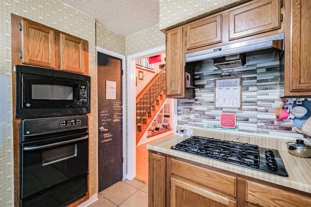 kitchen featuring light tile patterned flooring, decorative backsplash, a textured ceiling, and black appliances