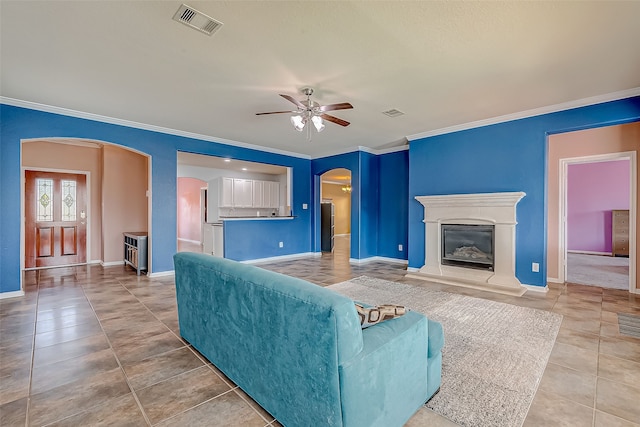 living room featuring ceiling fan, ornamental molding, and tile patterned flooring