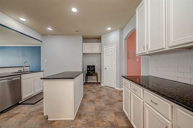 kitchen with sink, white cabinetry, dark stone countertops, stainless steel dishwasher, and a kitchen island