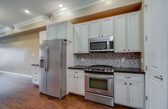 kitchen featuring appliances with stainless steel finishes, white cabinetry, dark stone countertops, backsplash, and dark wood-type flooring