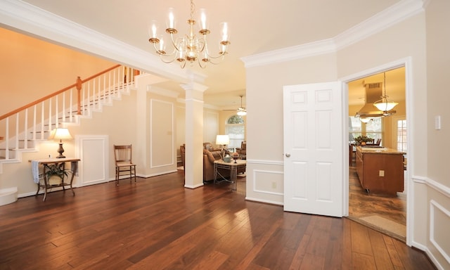 interior space with dark hardwood / wood-style flooring, ceiling fan with notable chandelier, ornamental molding, and ornate columns