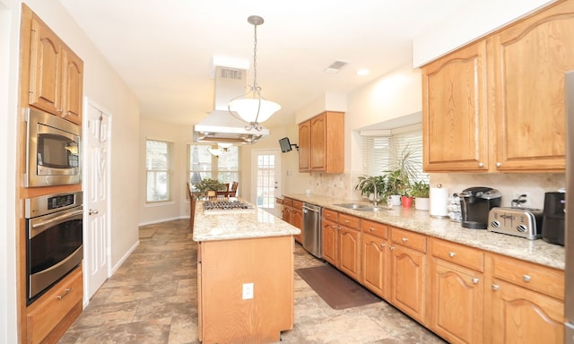 kitchen with sink, light stone counters, decorative light fixtures, a center island, and stainless steel appliances