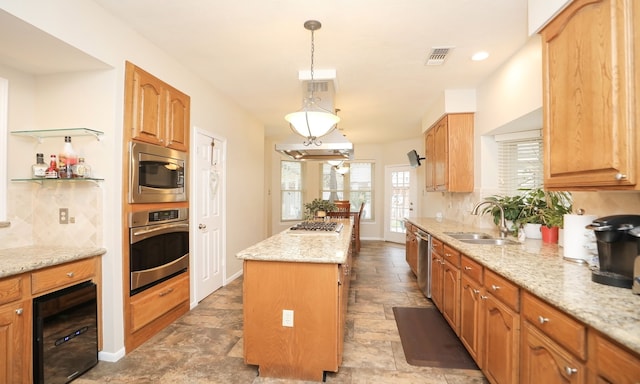 kitchen with a kitchen island, appliances with stainless steel finishes, pendant lighting, sink, and light stone counters