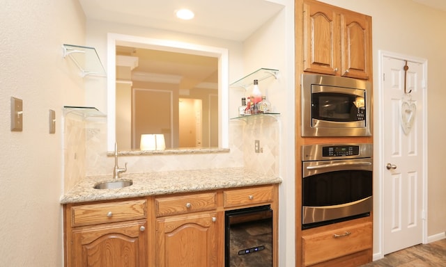 kitchen featuring sink, appliances with stainless steel finishes, backsplash, light stone counters, and light wood-type flooring