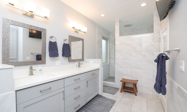 bathroom with a tile shower, vanity, tile patterned floors, and tile walls