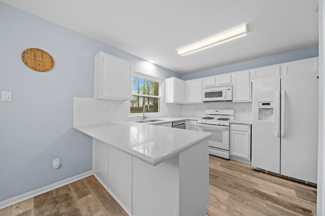 kitchen featuring white cabinetry, sink, backsplash, kitchen peninsula, and white appliances