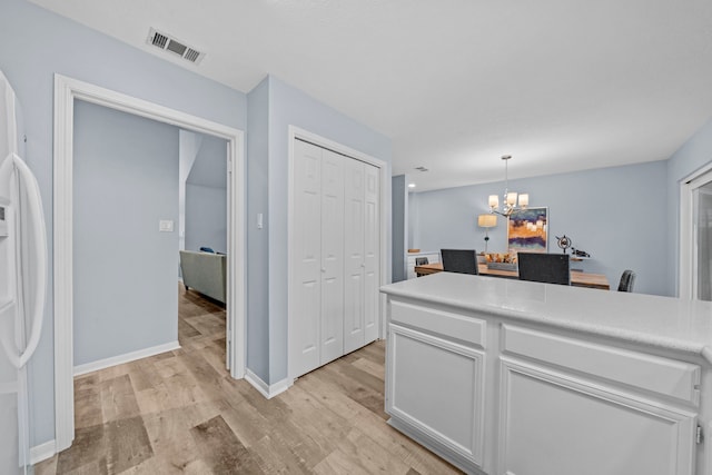 kitchen with a chandelier, white fridge with ice dispenser, pendant lighting, light hardwood / wood-style floors, and white cabinets