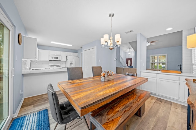 dining room featuring sink, ceiling fan with notable chandelier, and light hardwood / wood-style flooring