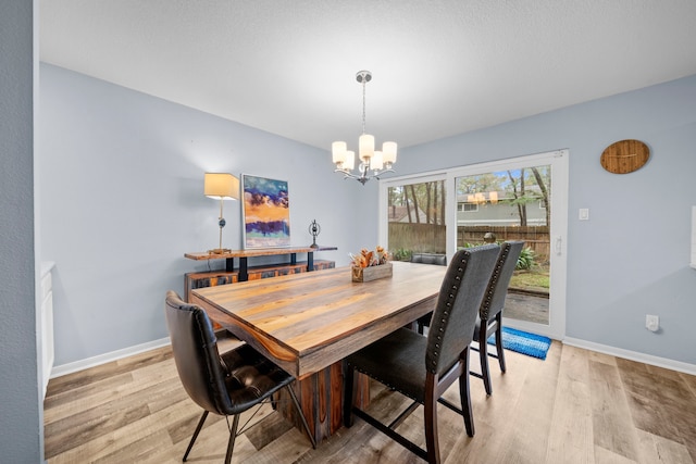 dining space featuring light hardwood / wood-style flooring and a notable chandelier