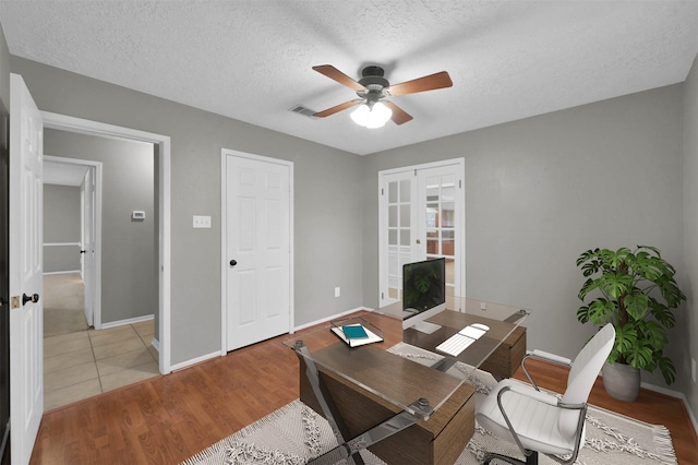 office featuring a textured ceiling, french doors, ceiling fan, and light wood-type flooring