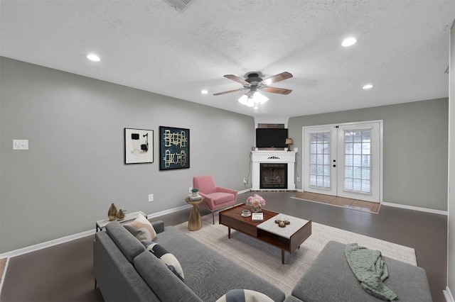 living room with french doors, ceiling fan, and a textured ceiling