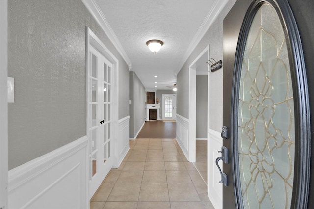 tiled entrance foyer with ornamental molding, a textured ceiling, and ceiling fan