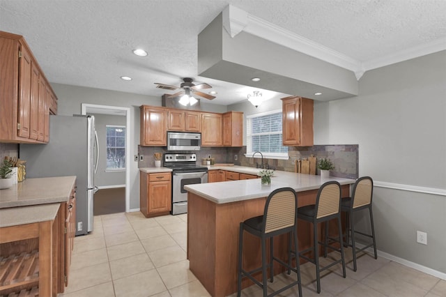 kitchen with sink, tasteful backsplash, light tile patterned floors, kitchen peninsula, and stainless steel appliances