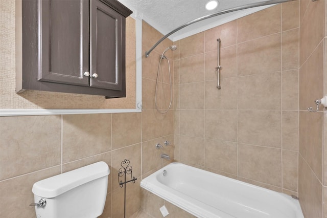 bathroom with tiled shower / bath combo, tile walls, a textured ceiling, and toilet