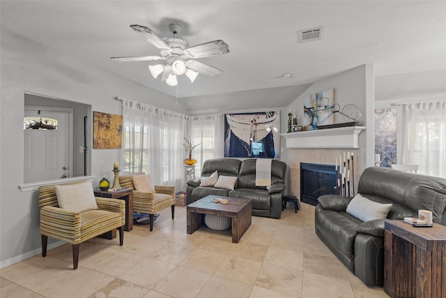 tiled living room featuring a tiled fireplace, lofted ceiling, and ceiling fan