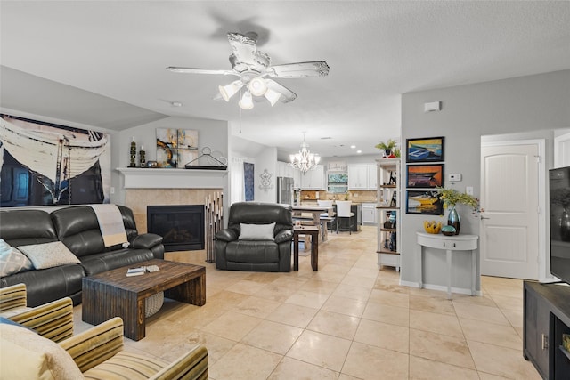 tiled living room with a tile fireplace and ceiling fan with notable chandelier