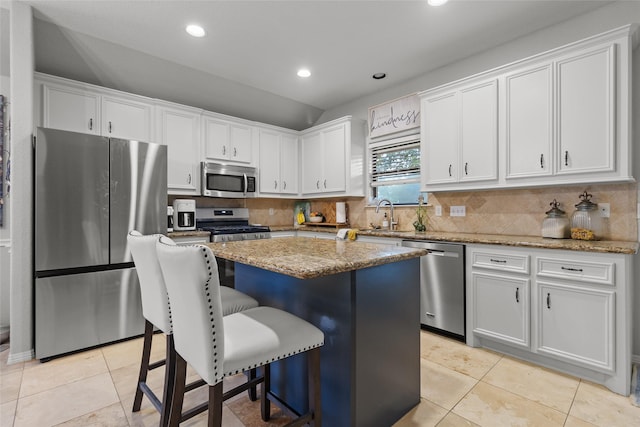 kitchen with light tile patterned floors, a kitchen island, white cabinets, and appliances with stainless steel finishes