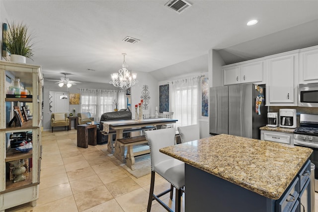 kitchen featuring a kitchen island, white cabinetry, appliances with stainless steel finishes, and lofted ceiling