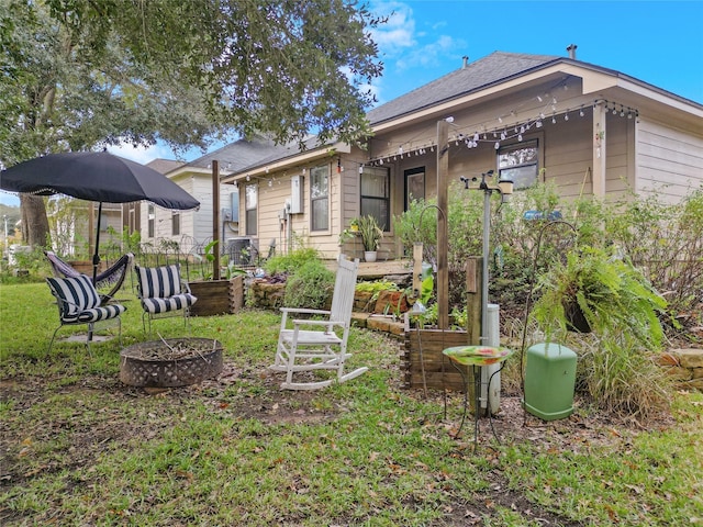 rear view of property with a fire pit and a lawn