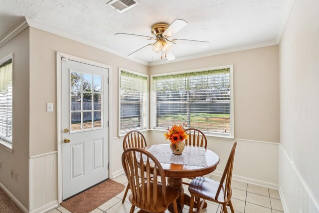 tiled dining space with crown molding and ceiling fan