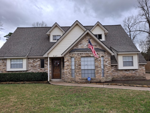 view of front facade featuring a shingled roof, brick siding, and a front lawn