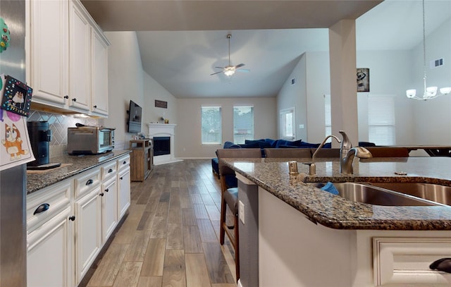 kitchen with hanging light fixtures, white cabinetry, sink, and decorative backsplash