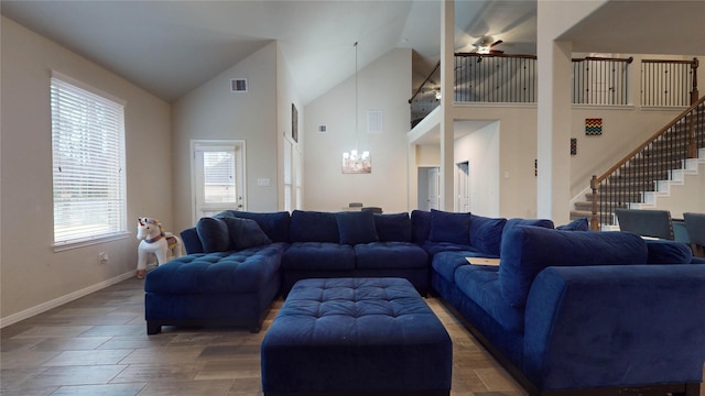 living room with ceiling fan with notable chandelier, a wealth of natural light, and high vaulted ceiling