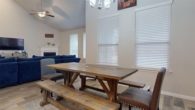 dining area featuring ceiling fan with notable chandelier, plenty of natural light, vaulted ceiling, and light wood-type flooring