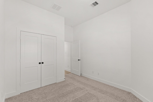 unfurnished bedroom featuring light colored carpet and a closet