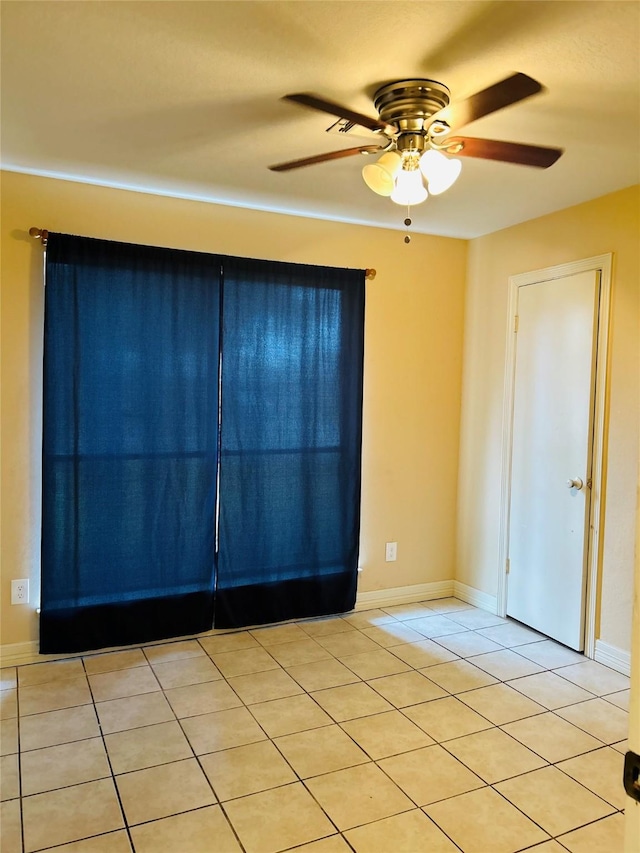 tiled spare room with ceiling fan