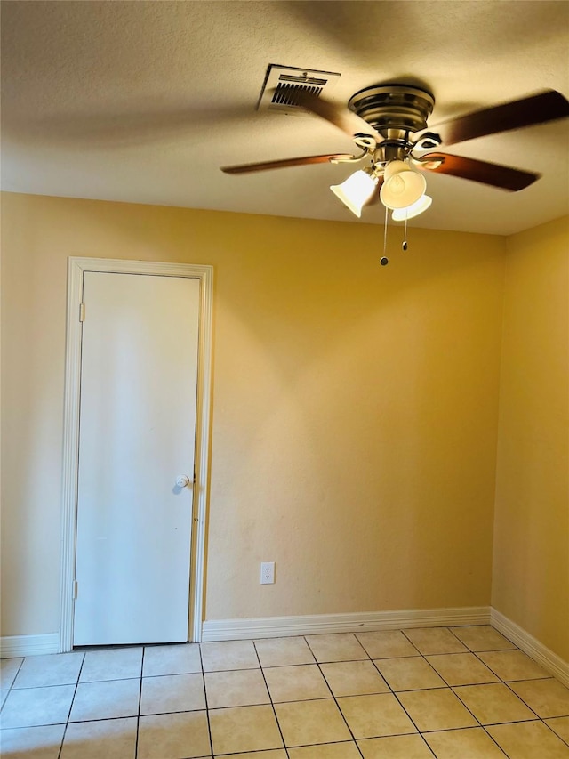 tiled empty room with ceiling fan and a textured ceiling