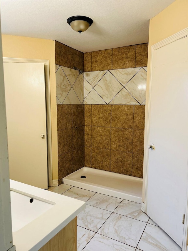 bathroom featuring tiled shower and sink