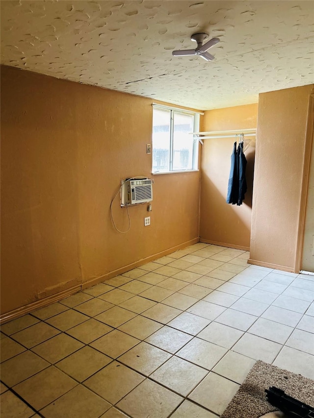 spare room with light tile patterned flooring, an AC wall unit, and ceiling fan