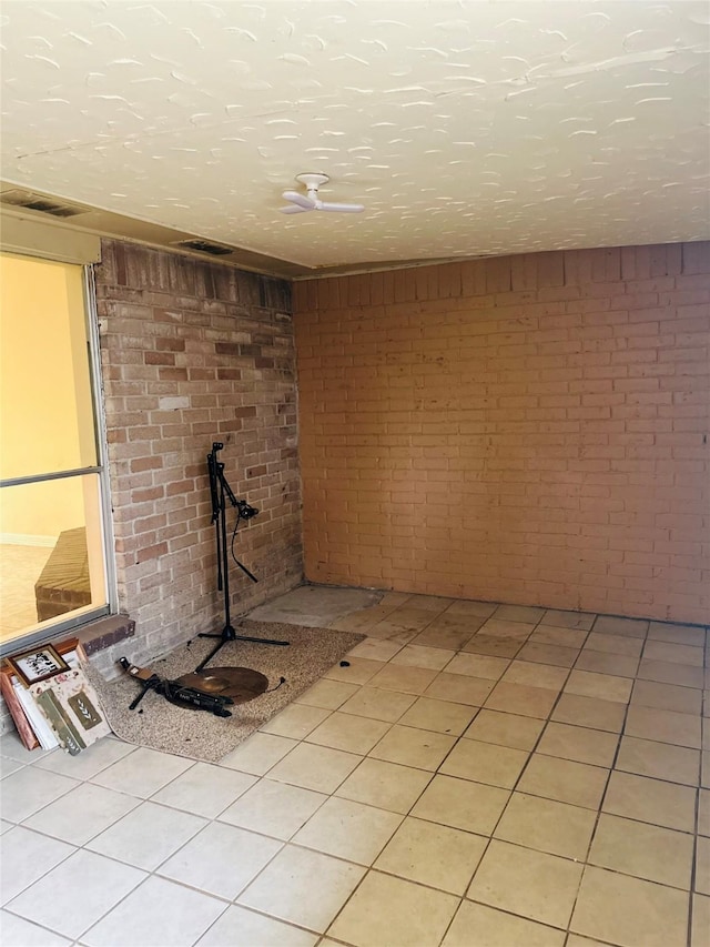 basement with light tile patterned flooring, brick wall, and a textured ceiling