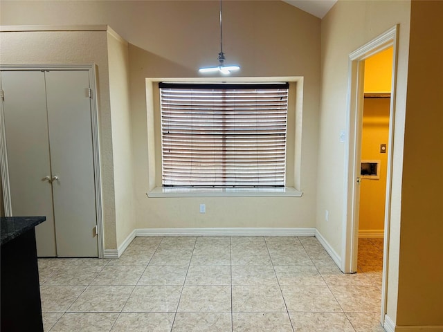 unfurnished dining area with lofted ceiling and light tile patterned flooring