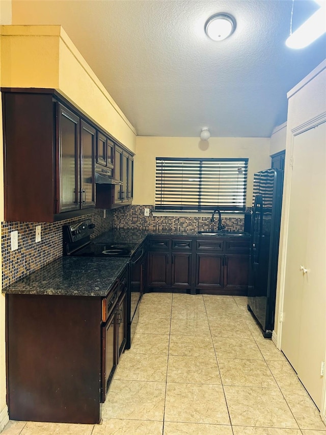 kitchen featuring sink, black appliances, a textured ceiling, decorative backsplash, and dark stone counters