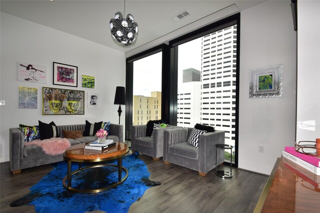 living room with dark wood-type flooring, a chandelier, and a wall of windows