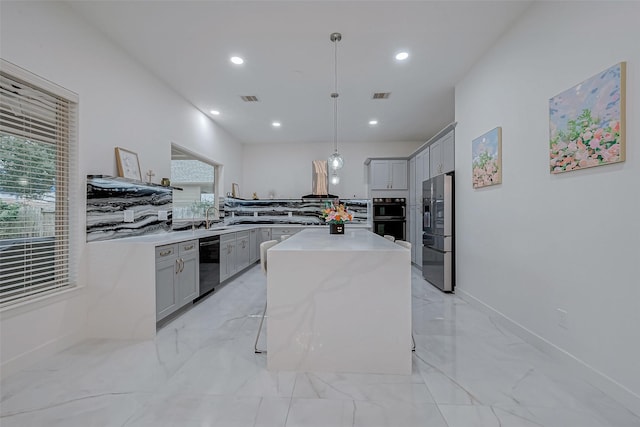 kitchen featuring decorative light fixtures, sink, a breakfast bar area, a center island, and black appliances