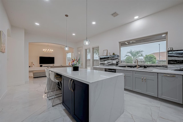 kitchen featuring pendant lighting, a wealth of natural light, a center island, and gray cabinetry