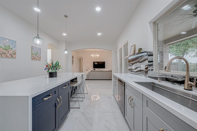 kitchen with dishwasher, sink, a kitchen breakfast bar, and decorative light fixtures