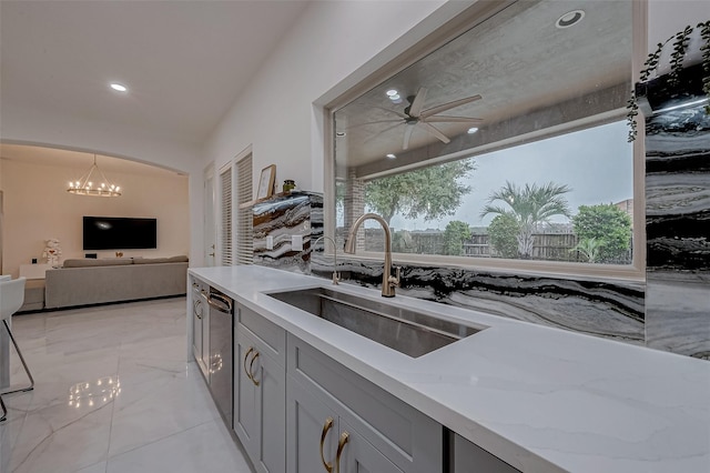 kitchen with dishwasher, light stone countertops, sink, and gray cabinetry