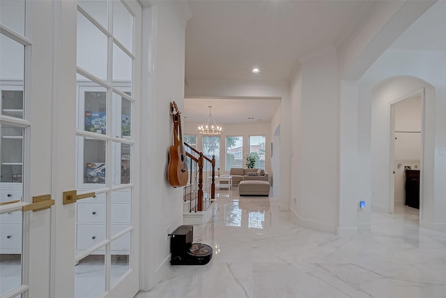 hallway with ornamental molding and a notable chandelier