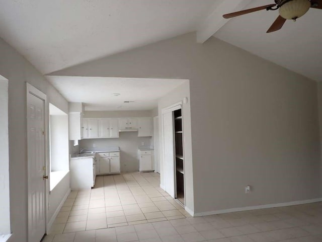 kitchen featuring light tile patterned flooring, sink, lofted ceiling with beams, ceiling fan, and white cabinets