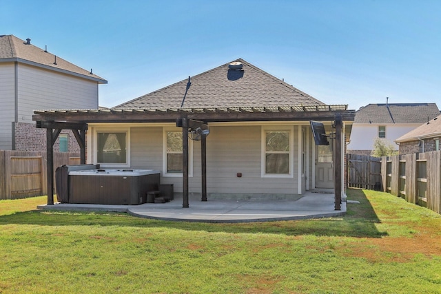 rear view of property featuring a hot tub, a patio, and a yard