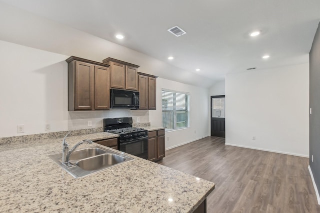 kitchen featuring dark brown cabinetry, sink, kitchen peninsula, hardwood / wood-style floors, and black appliances