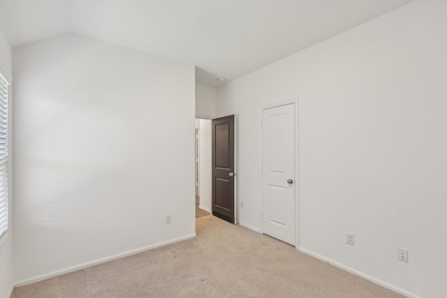 carpeted empty room featuring lofted ceiling