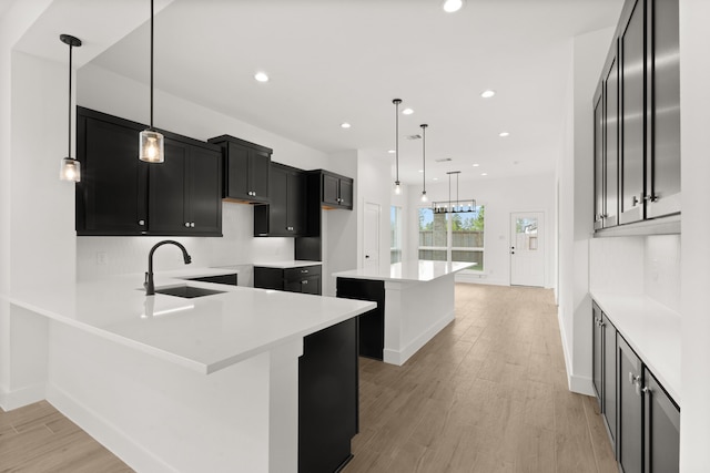 kitchen with sink, light hardwood / wood-style flooring, a breakfast bar, decorative light fixtures, and kitchen peninsula