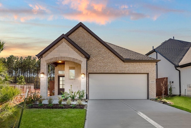 french country style house with a garage and a lawn